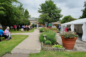 A heritage centre with members sitting on the left hand side eating picnics and on the right hand side, a marquee