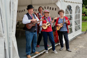 Members of Broomfield u3a ukulele group standing in red and blue clothing holding ukulele