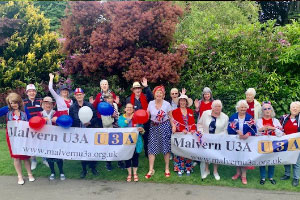 Malvern u3a members holding a malvern u3a sign and red and blue balloons