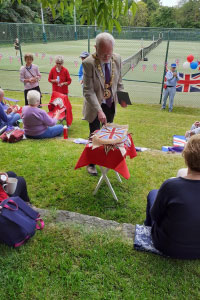A man outside cutting into a cake