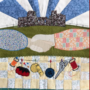 A fabric square which shows a building with triangular blue and white pieces representing the sky and two hands meeting together in a handshake in the foreground of the picture