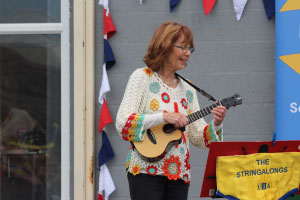 A woman in a crochet top playing the ukelele