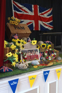 A display showing a picnic basket, a union jack flag, flowers and u3a bunting
