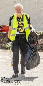A man in a high vis jacket holding a bin bag walking down the street
