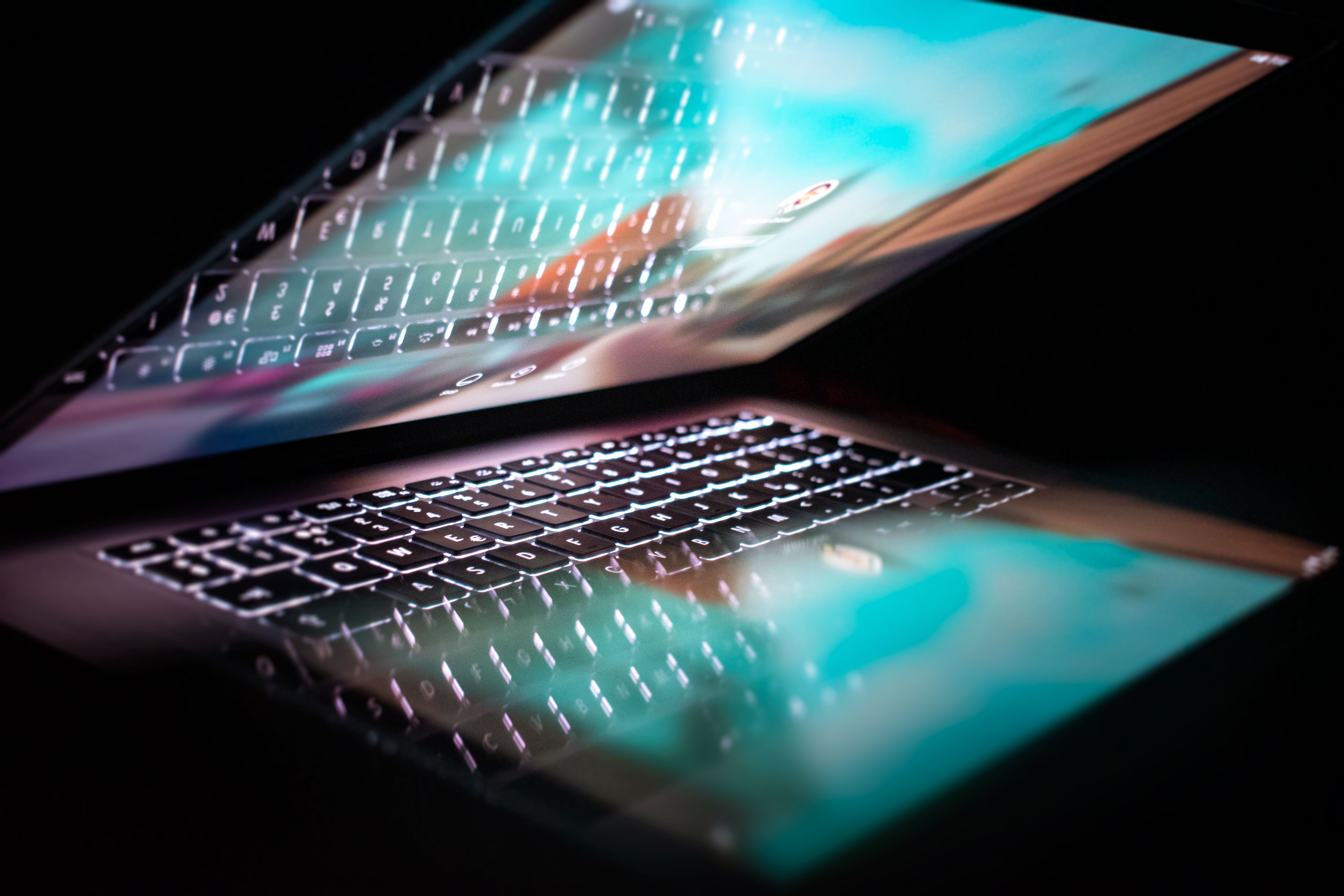 a half closed laptop with lit up screen and keyboard