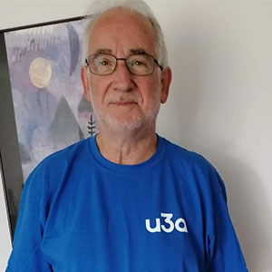 A man in a blue t-shirt with a u3a logo is smiling at the camera