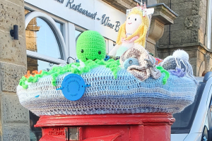a postbox with a knitted covering with an octopus and mermaid
