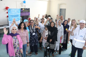 A group of people smiling and raising their hands at the camera