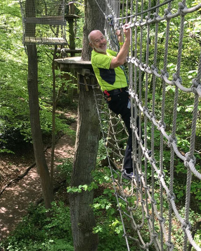 A man on an adventure course in a forest. 