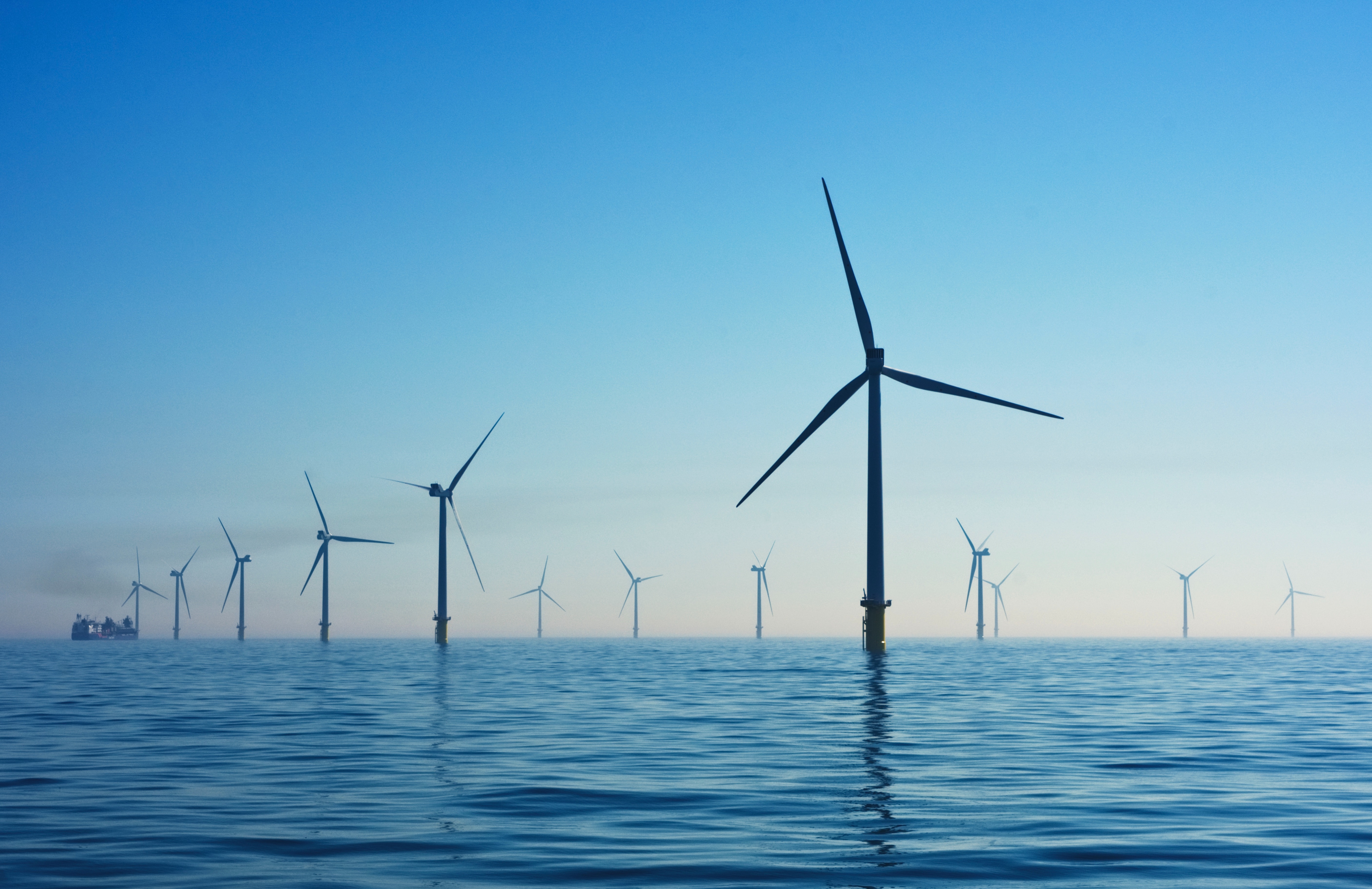 an offshore wind farm. the sea is calm and the sky is blue.