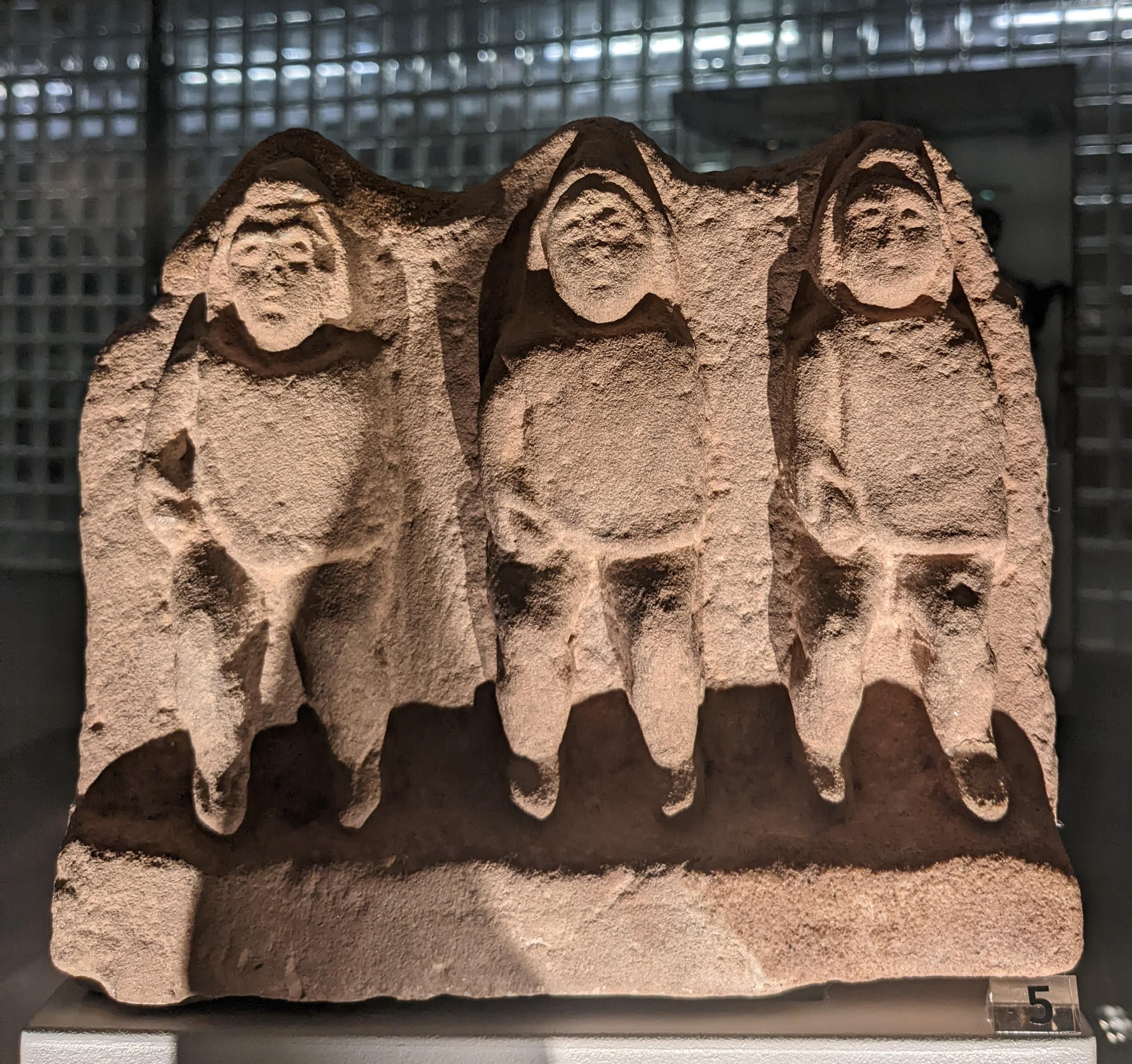 stone carving of three people