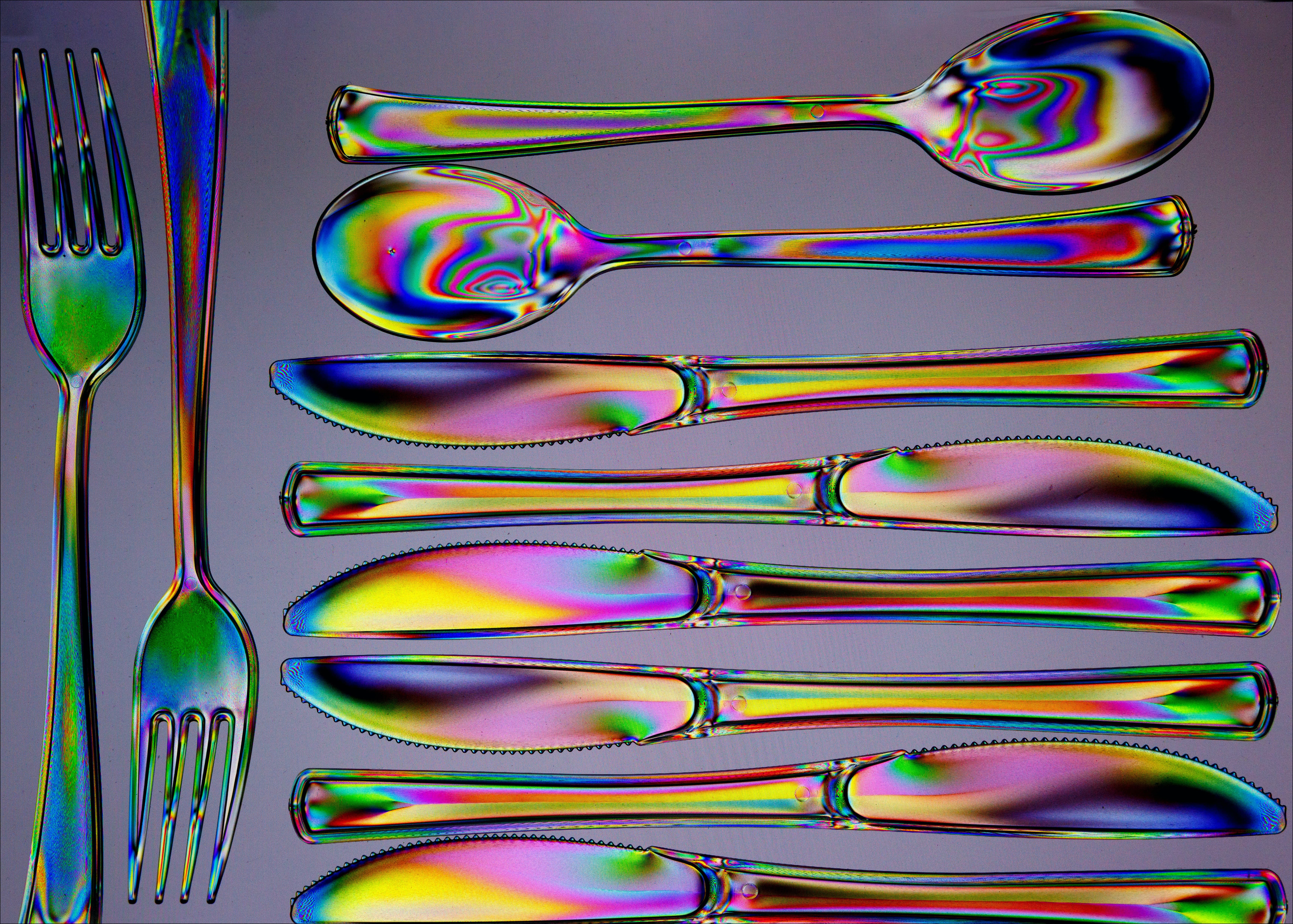 knives forks and spoons with swirly colourful patters on them laid out flat 