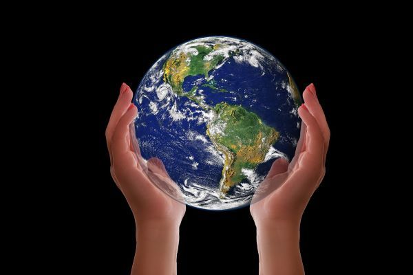 two hands holding an image of the earth, on a black background