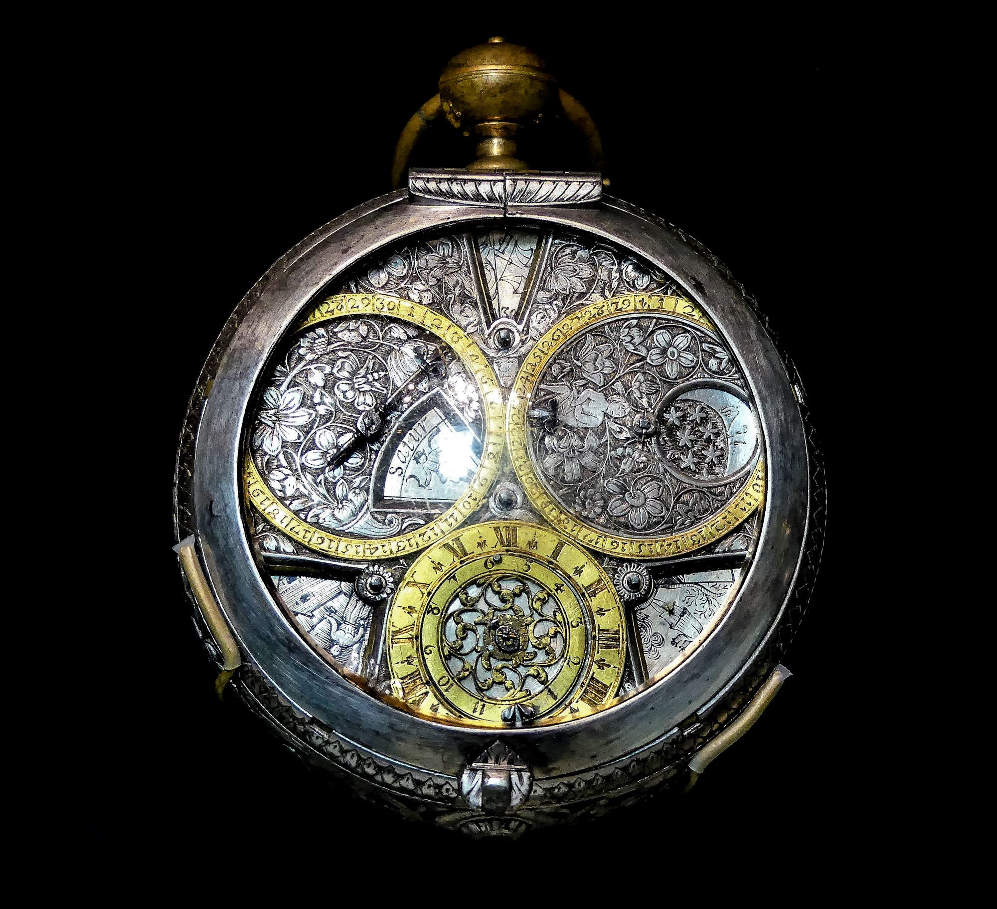 a silver and gold intricately made pocketwatch on a black background