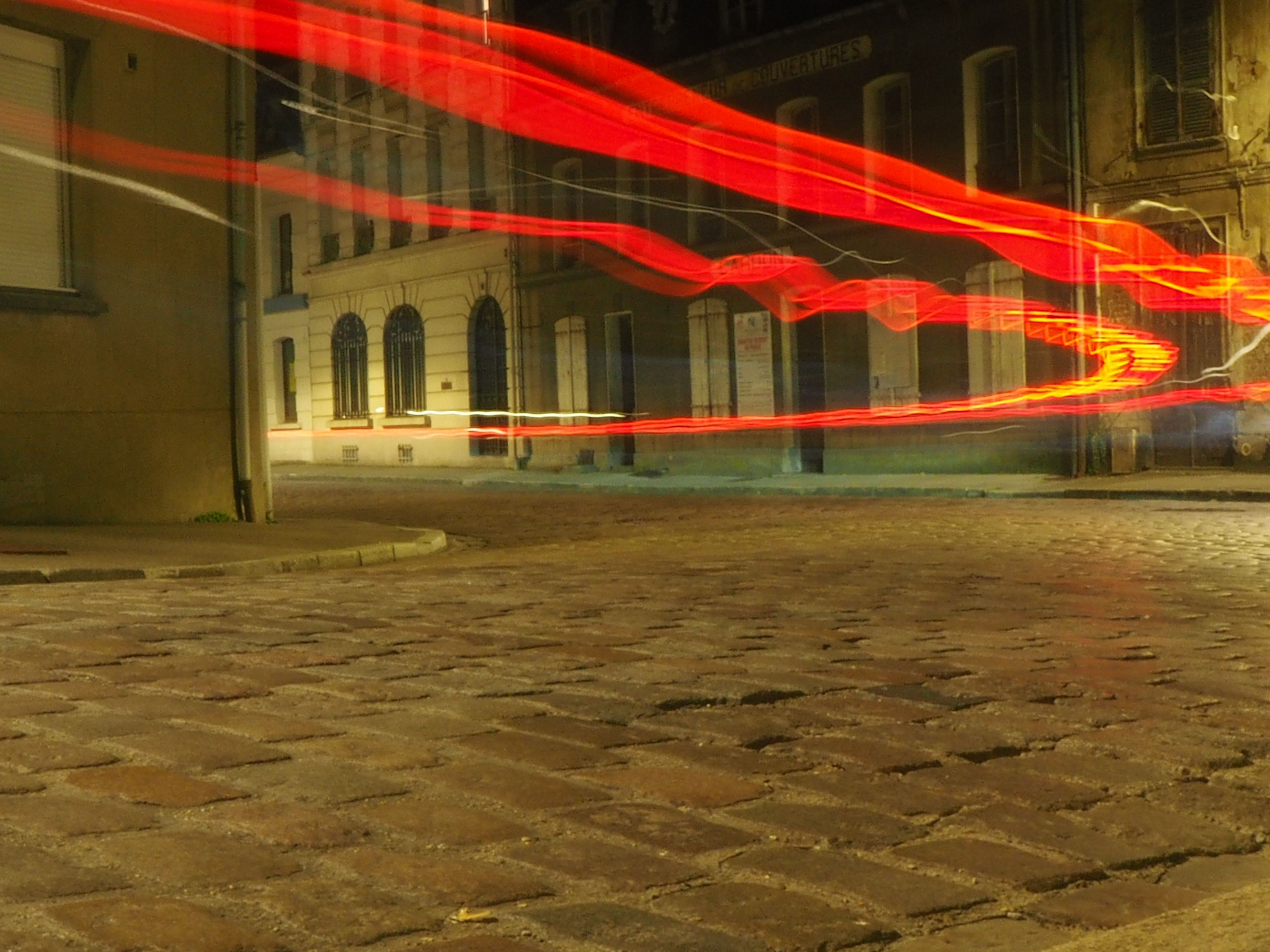 swirly red light lines from long exposure on a brick road