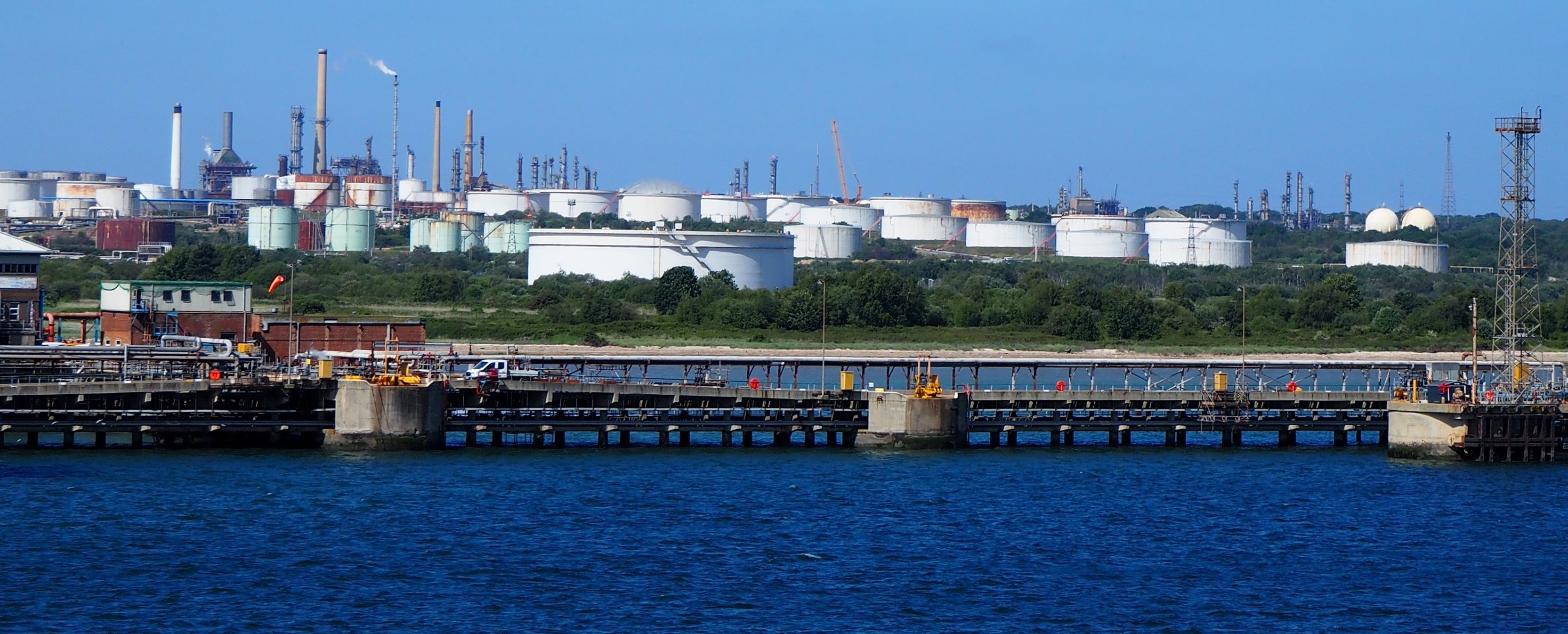 blue sea in front and white circular buildings across the water in background. 