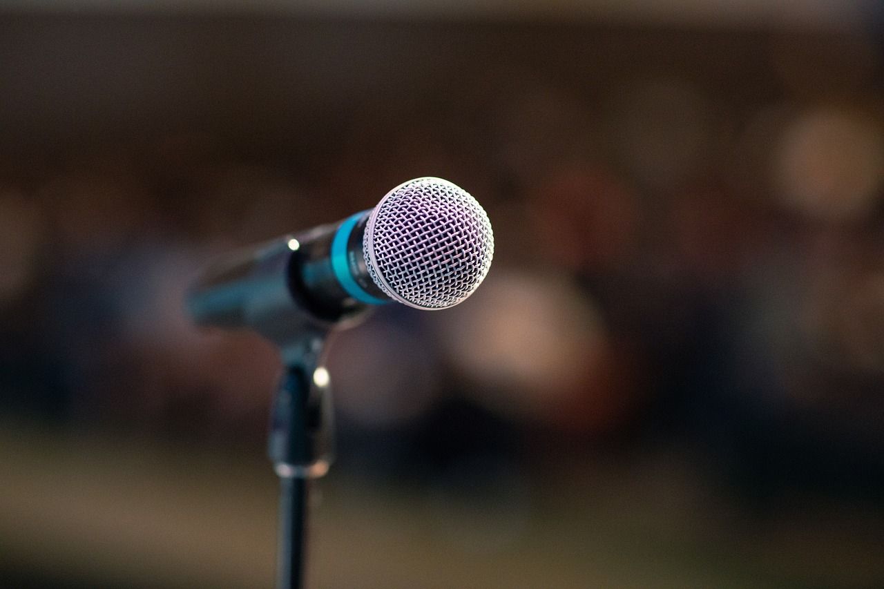 A microphone with a black handle and silver head. the background is blurred. 
