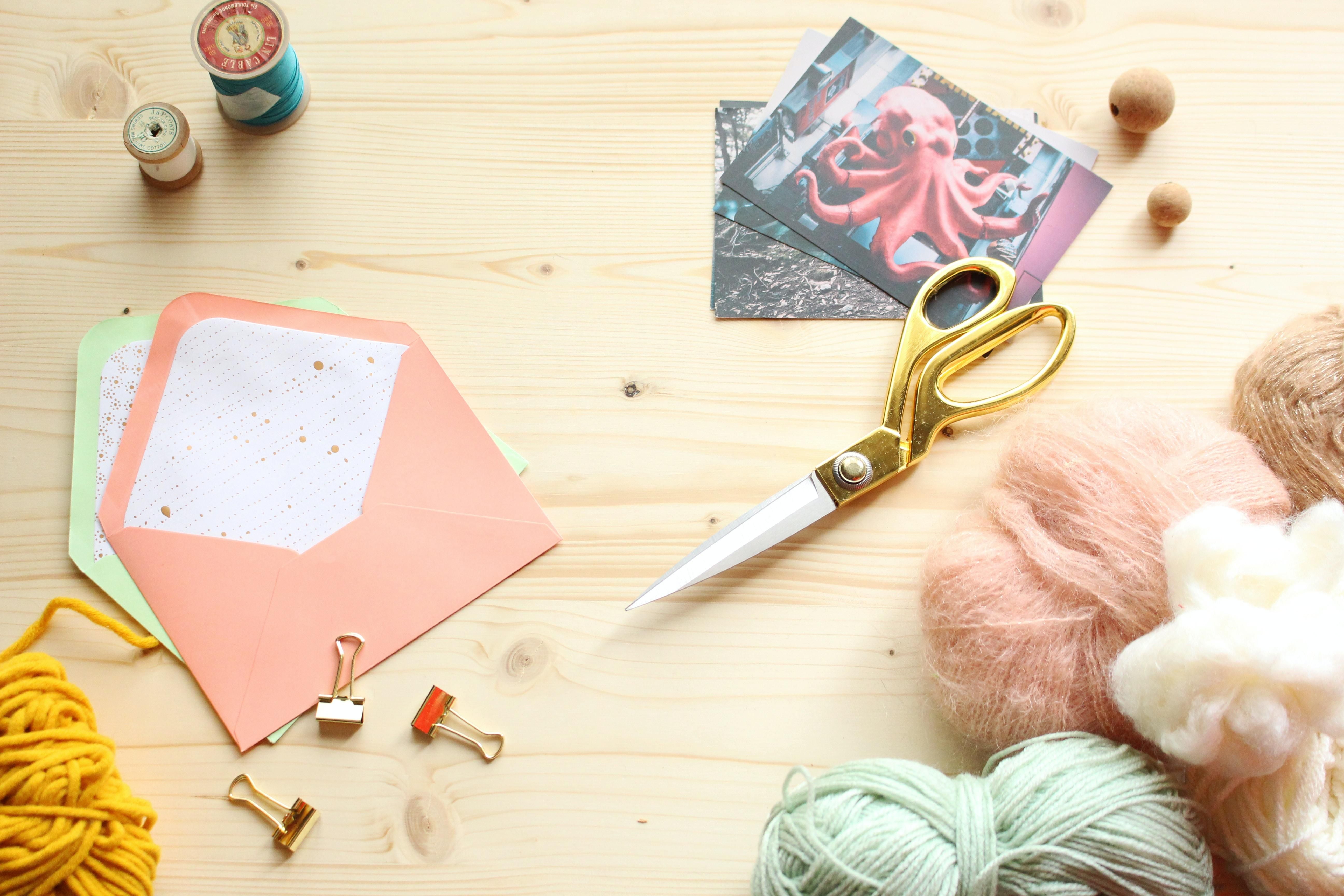 colourful craft materials such as wool and scissors laid out on a wooden table