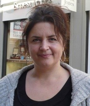 woman with hair up smiling in silver hoop earring and grey cardigan