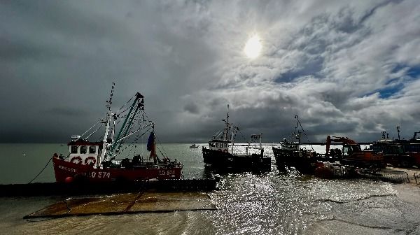 Small weather-worn fishing boats in front of a dramatic cloudy sky
