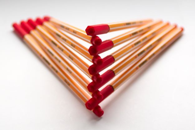 red and yellow pens stacked up in a precarious triangle shape