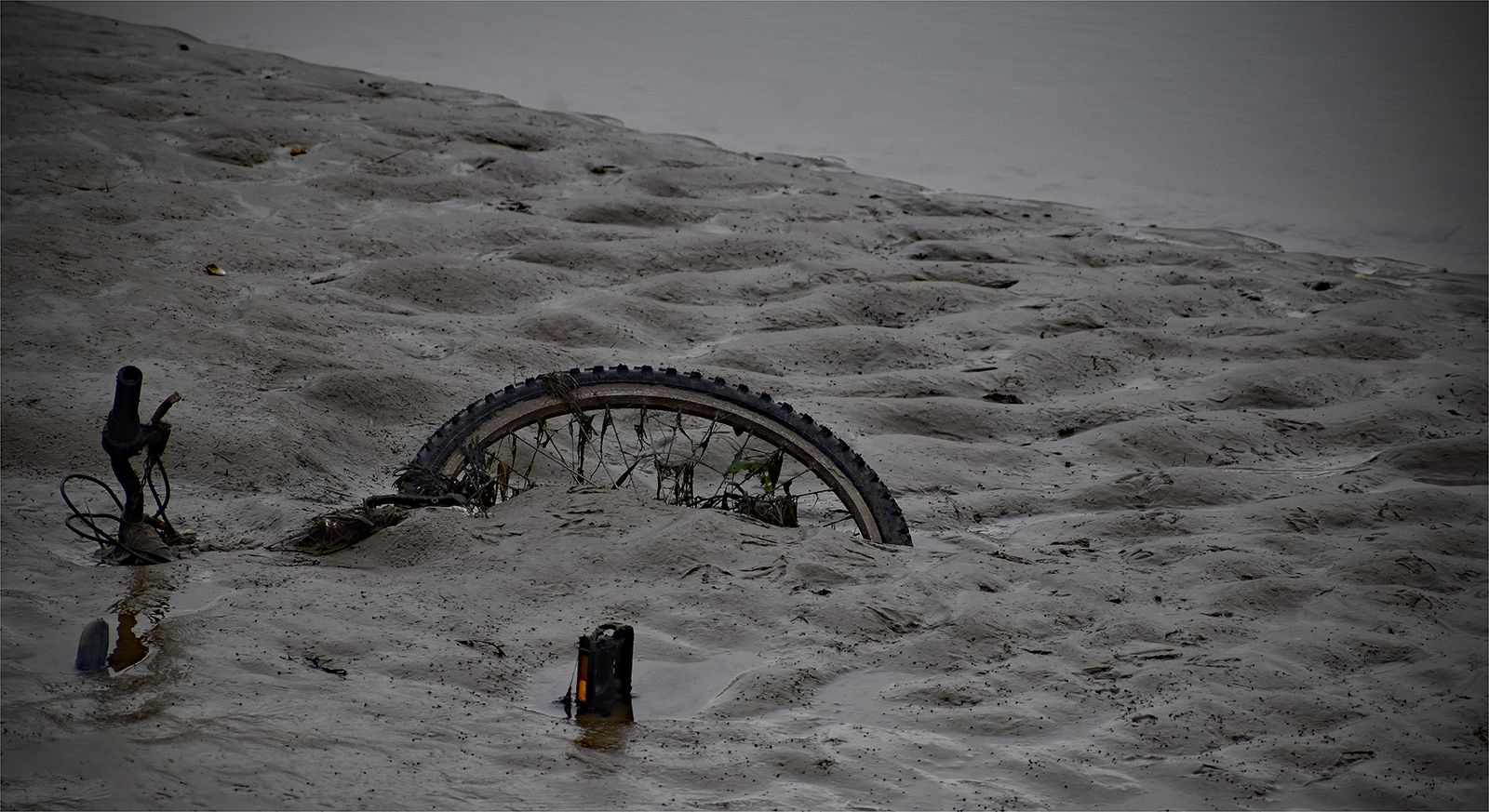 a bike wheel stuck in the mud, sunk