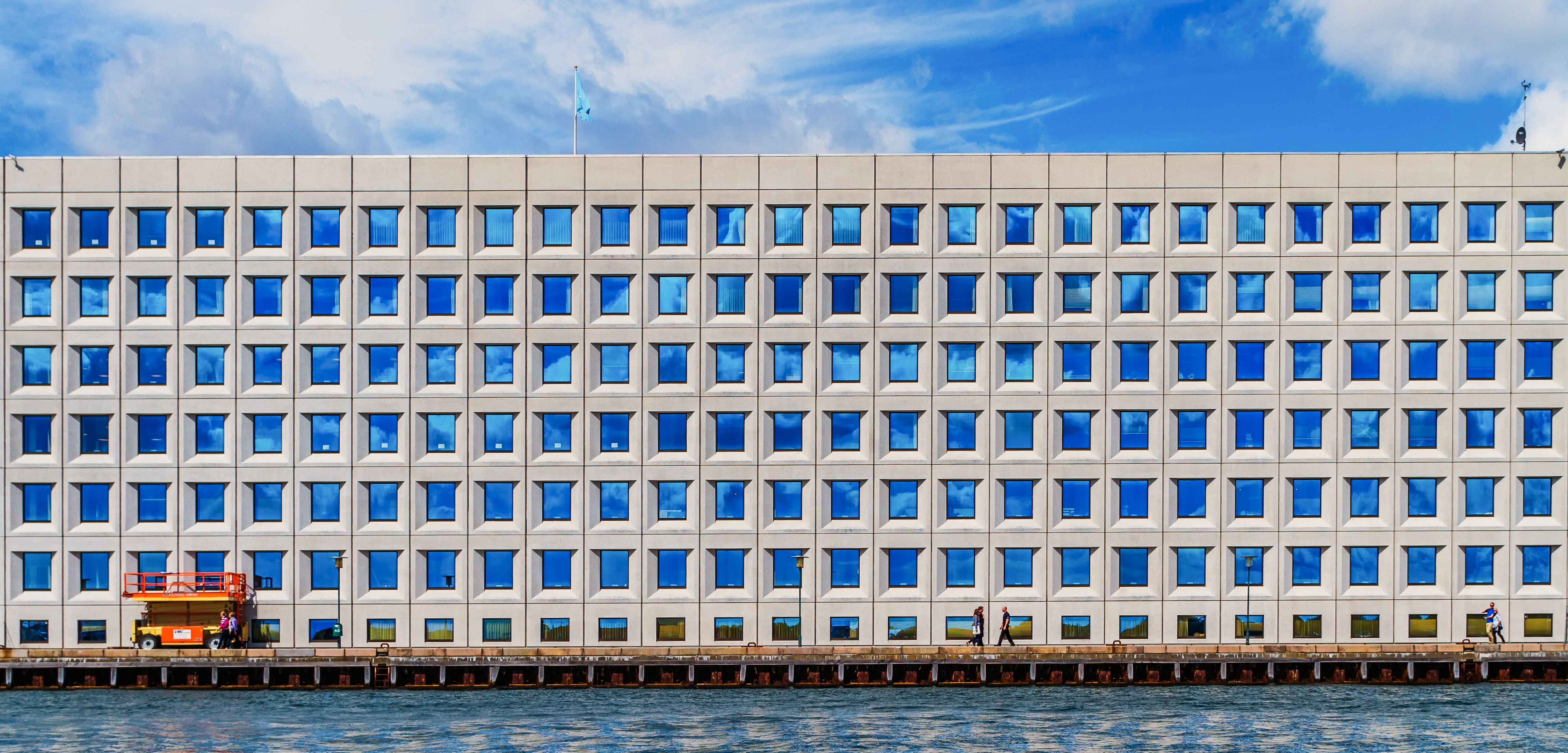 a blue sky showing a big office complex building with hundreds of blue square windows. 